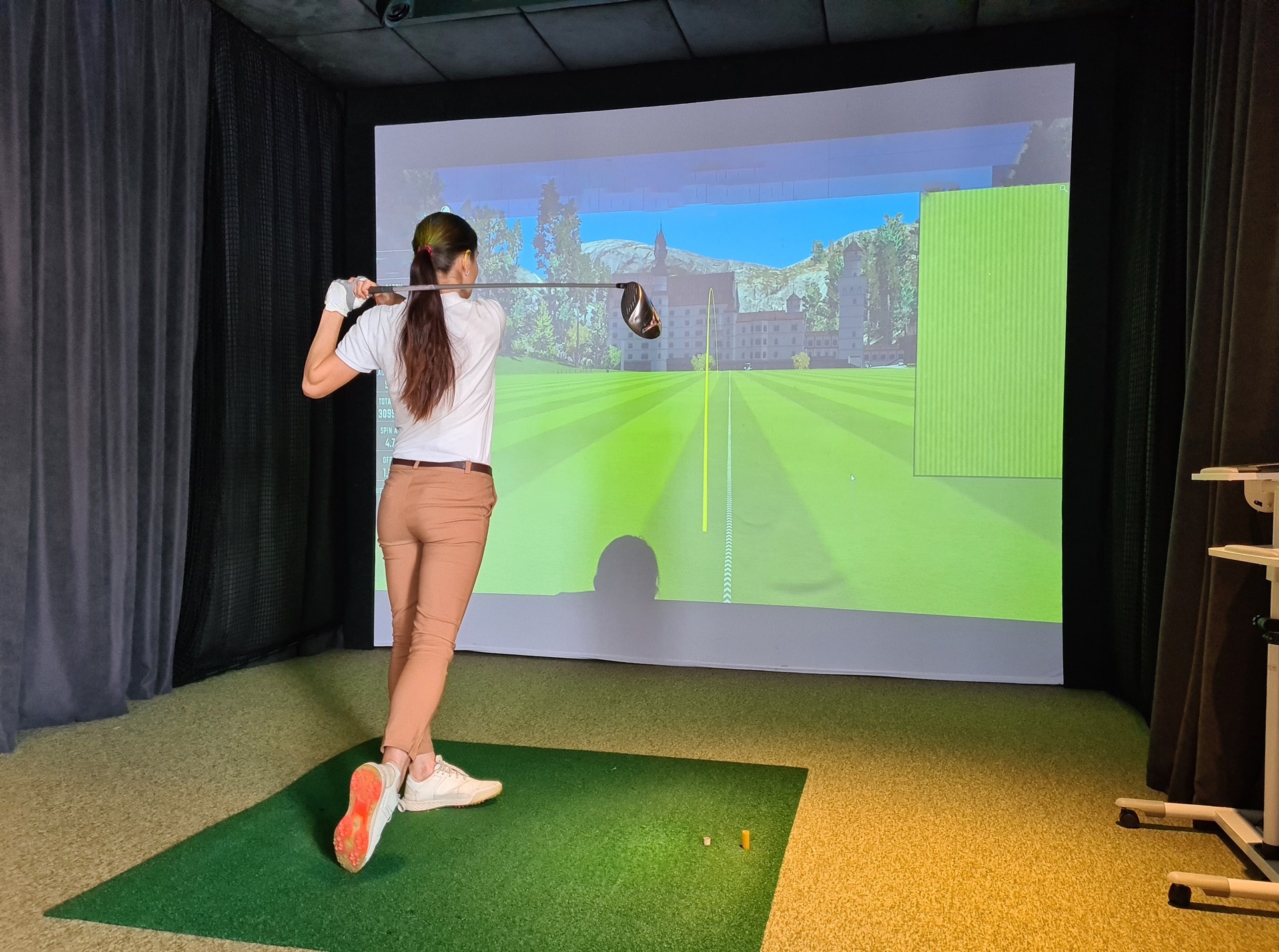 Female golfer plays golf on golf simulator